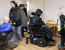 Zwei Personen im Rollstuhl und zwei weitere in einem neuen Haus.