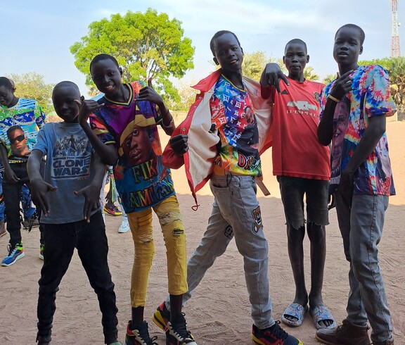 Eine Gruppe junger südsudanesischer Burschen grinst und macht coole Posen für die Kamera.