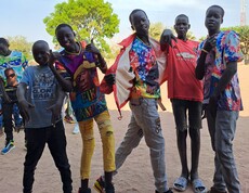 Eine Gruppe junger südsudanesischer Burschen grinst und macht coole Posen für die Kamera.