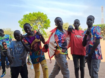 Eine Gruppe junger südsudanesischer Burschen grinst und macht coole Posen für die Kamera.
