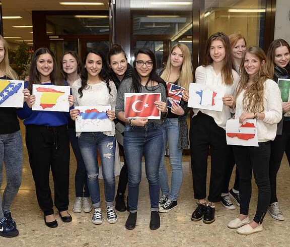 SchülerInnen halten in den Händen A4 Blätter wo unterschiedelchen Nationalflaggen aufgezeichnet sind.