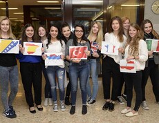 SchülerInnen halten in den Händen A4 Blätter wo unterschiedelchen Nationalflaggen aufgezeichnet sind.