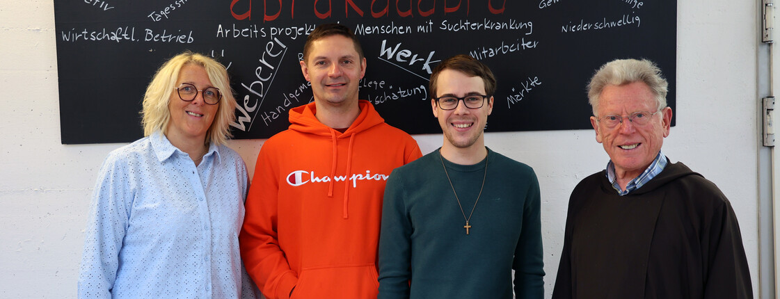 Eine Frau und drei Männer, einer davon Priester, stehen vor einer Tafel mit der Aufschrift "abrakadabra".