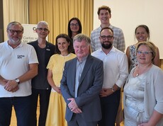 Eine Gruppe von Erwachsenen steht beisammen und schaut in die Kamera