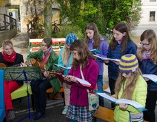 junge Mädchen singen während wie junge Frauen sie mit der Gitarre begleiten.