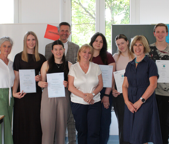 Schüler*innen und Lehrpersonen halten Zertifikate für Peer-Mediation, Gruppenfoto im Klassenraum