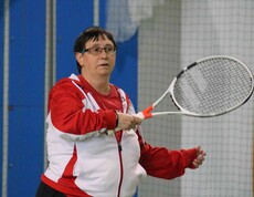 Frau in rotweissrotem Trikot mit Tennisschläger