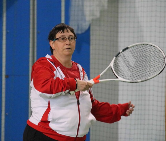 Frau in rotweissrotem Trikot mit Tennisschläger