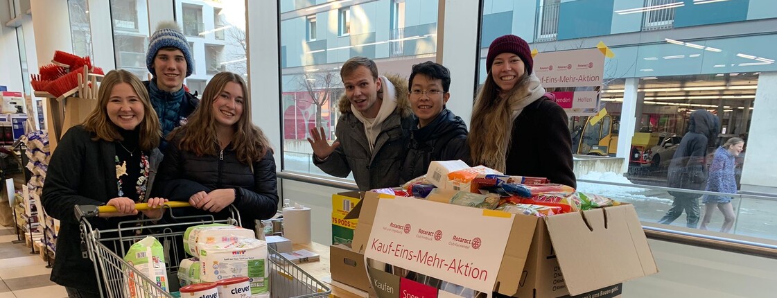 Sechs Jugendliche stehen mit zwei vollen Einkaufswägen in einem Supermartk.