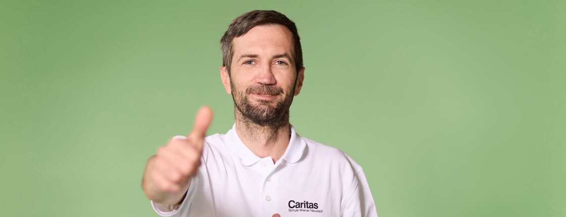 Schüler, der das Daumenhochzeichen in die Kamera hält, grüner Hintergrund