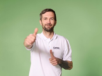 Schüler, der das Daumenhochzeichen in die Kamera hält, grüner Hintergrund