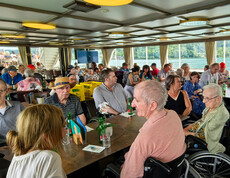 Reisegruppe von Haus Klara sitzt an Tischen auf einem Schiff und fährt über den Wörthersee.