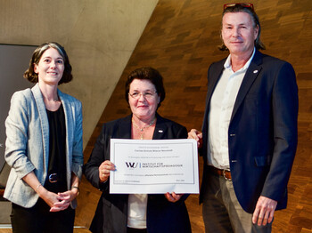 Drei Personen halten eine Urkunde in der Hand