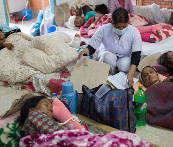 Medizinische Versorgung in Nepal: Menschen liegen in Decken gehüllt am Boden.