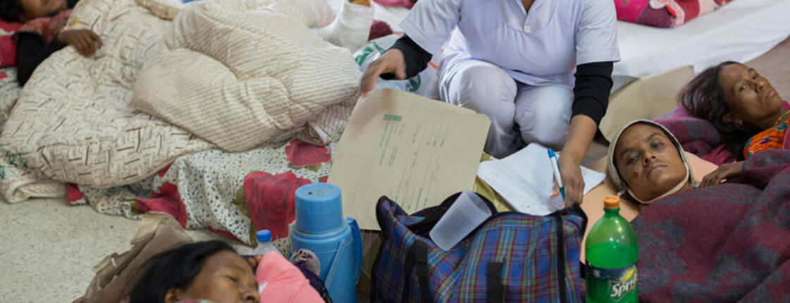 Medizinische Versorgung in Nepal: Menschen liegen in Decken gehüllt am Boden.