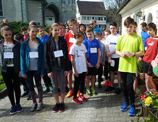 Junge Burschen und Mädchen versammeln sich für ein Gruppenfoto. Sie tragen alle Sportkleidung und ein Namensschild.