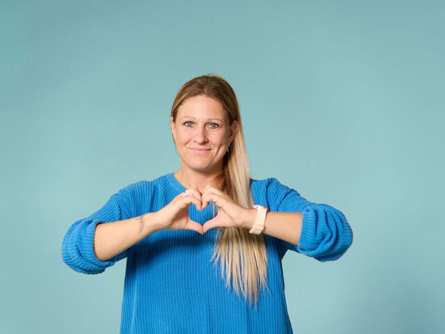 Dame, die mit beiden Händen ein Herz formt