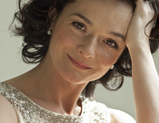 Eine junge Frau strahlt in die Kamera. Sie hat kinnlange, braune Haare.