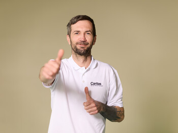 ein Mann, der Daumen hoch zeigt und schmunzelt