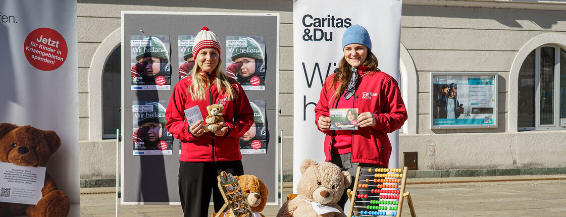 Zwei Frauen präsentieren Infomaterial vor Bäreninstallation zur Frühförderung am Neuen Platz.