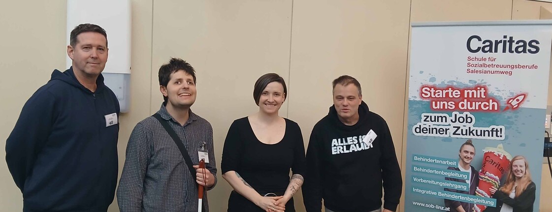 Vier Personen vor einem Plakat.