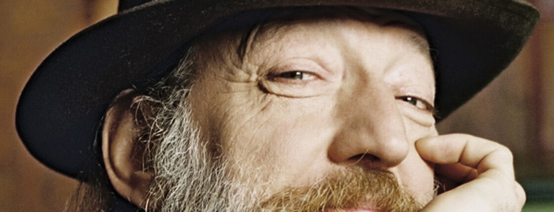 Ein Porträt eines Herrn mit langem Bart. Er trägt einen Hut aus Stoff.