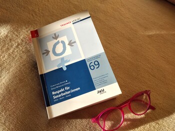Buch liegt am Boden und neben dem Buch eine rote Brille