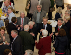 Personen stehen zusammen und trinken ein Glas Wein