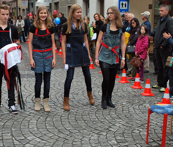 Drei junge Erwachsene und ein junger Erwachsener präsentieren am carla Reuse Day modische Kleidung den ihnen umringenden Personen. Alle vier haben blonde Haare. 