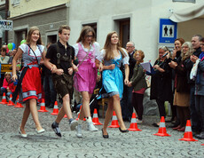 Drei junge Erwachsene und ein junger Erwachsener gehen Hand in Hand in Tracht am carla Reuse Day durch die Innenstadt. Die drei Frauen tragen jeweils bunte Dirndl und der junge Herr klassisch Lederhosen. 