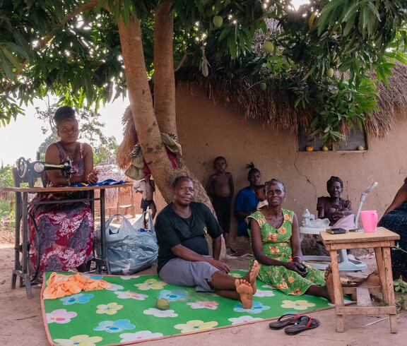 Mehrere Erwachsene im Südsudan sitzen vor einer Lehmhütte.