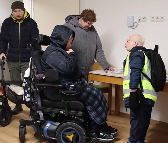 Eine Person im Rollstuhl und drei weitere in einem neuen Haus.