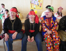 Fasching in er Werkstätte Bludenz. Menschen mit Behinderung sind verkleidet und geschminkt. Sie schneiden dabei fröhliche Grimassen. 