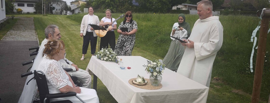 Brautpaar im Rollstuhl und Pastoralassitent, Sängerinnen im Hintergrund 