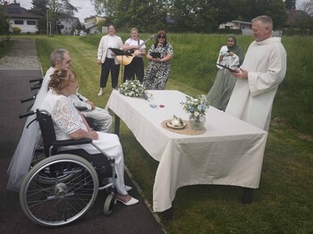 Brautpaar im Rollstuhl und Pastoralassitent, Sängerinnen im Hintergrund 