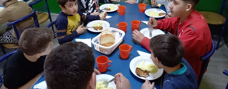 Eine Gruppe Kinder sitzt am Tisch und isst. 