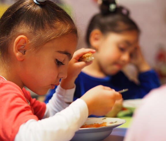 Zwei Kinder essen eine warme Gemüsesuppe.