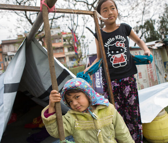 Zwei Mädchen stehen neben einem Zettel und schauen traurig in die Kamera