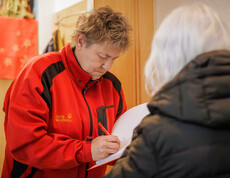 Person trägt Daten in eine Spendenliste ein, Margit Müller steht daneben.