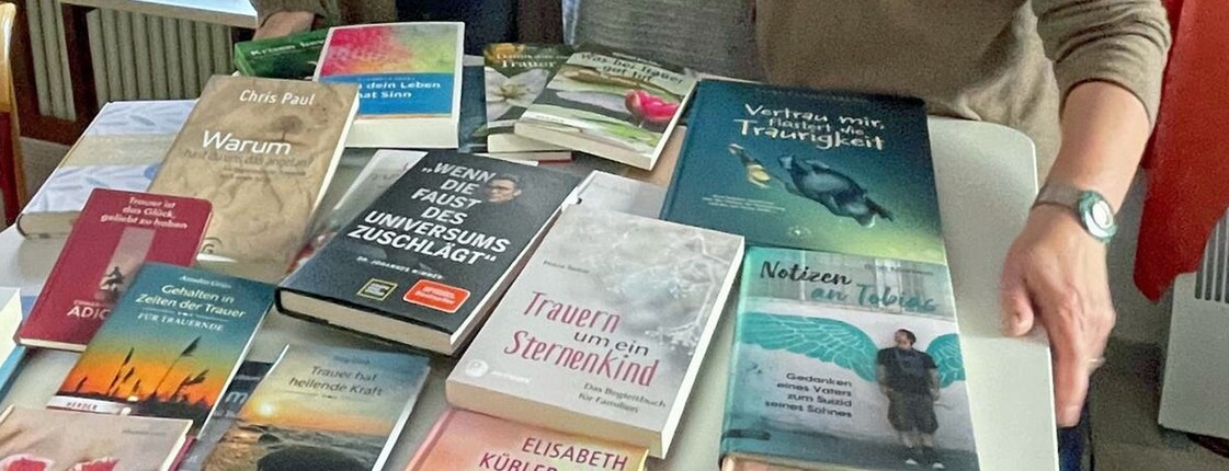 Drei Frauen stehen hinter einem Tisch auf dem Bücher liegen.