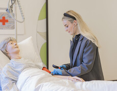 Eine junge Frau über an einer Pflegepuppe