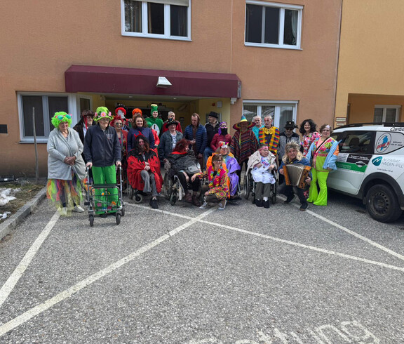 Große Gruppe verkleideter Bewohner*innen und Mitarbeitender vor dem Eingang von Haus Klara während der Faschingsfeier.