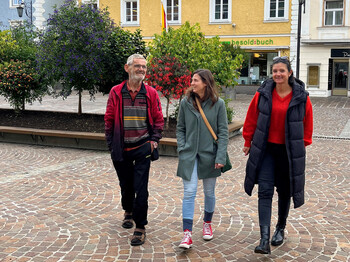 Drei Personen spazieren plaudernd beim gemeinsamen Spazierengehen.