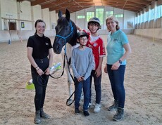 Vier Personen und ein Pferd in der Reithalle