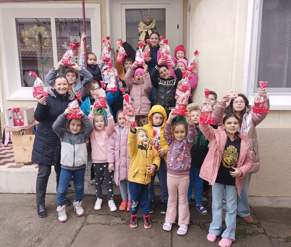 Eine Gruppe Kinder hält strahlend ihre Nikolausgeschenke in die Höhe.