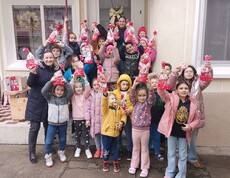 Eine Gruppe Kinder hält strahlend ihre Nikolausgeschenke in die Höhe.