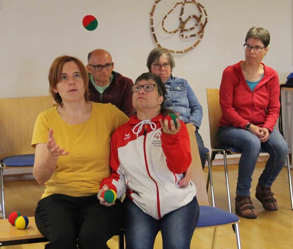 Zwei Personen werfen Bälle in die Luft, einige Zuseher