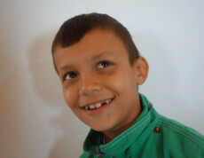 Ein Junge aus dem Kinderzentrum Eden lächelt strahlend und schaut hoffnungsvoll nach oben.