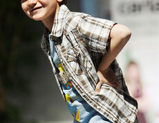 carla Modeschau: Ein junger Bub mit einer roten Schildkappe und einem grau-braun karierten Hemd läuft auf dem Laufsteg. Er ist erfreut über die ihm zugestandene Aufmerksamkeit. 