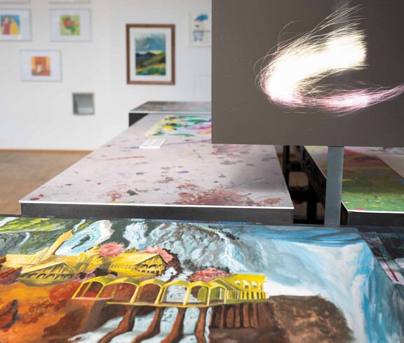 Verschiedene Bilder liegen auf einem Tisch im Hintergrund ist ein schwarzer Monitor mit einem hellen Kreis